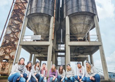 Gruppe junger Frauen bei einem gemeinsamen Fotoshooting vor einer Industrieanlage