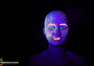 Portrait einer Frau mit fluoreszierender Gesichtsfarbe unter Schwarzlicht