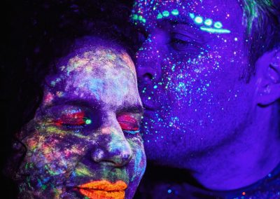 Zwei Personen mit fluoreszierender Gesichtsfarbe bei einem Schwarzlicht-Fotoshooting