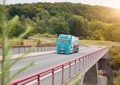 Unternehmens-Lkw unterwegs auf einer Brücke in landschaftlicher Umgebung
